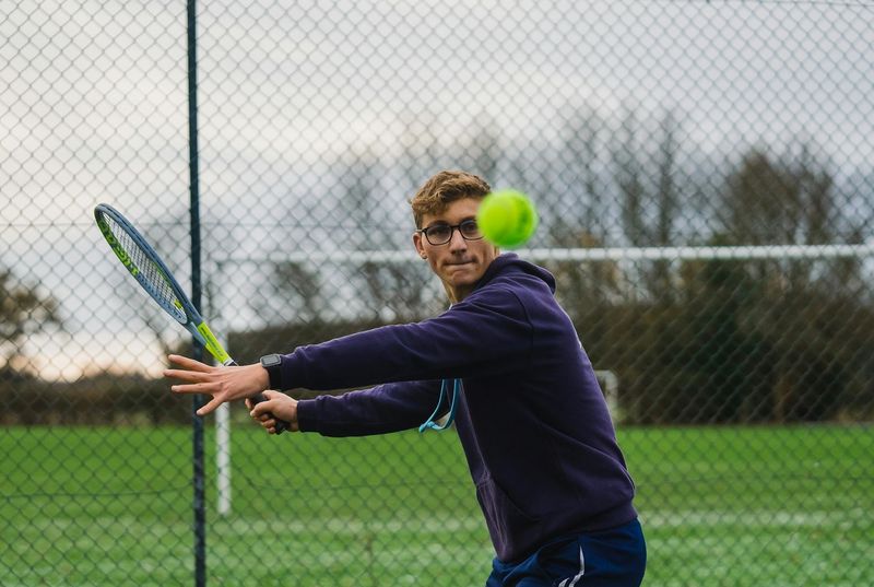 a tennis player about to hit a tennis ball on an outdoor tennis court