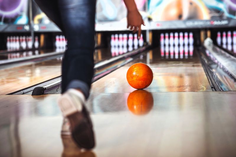 a person who just released a bowling ball down a bowling lane