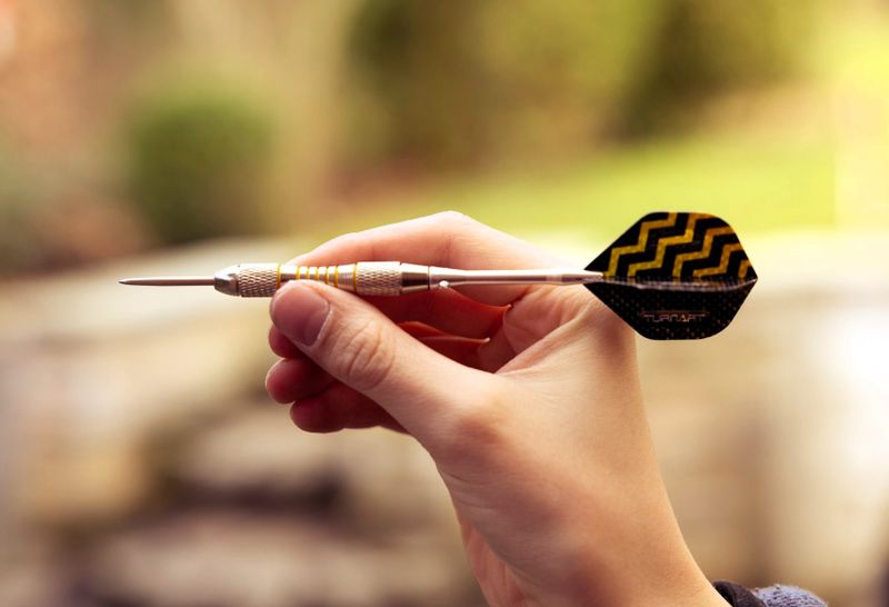 a hand holding a single dart