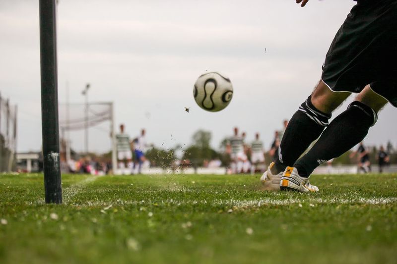 a soccer player wearing long socks taking a corner kick