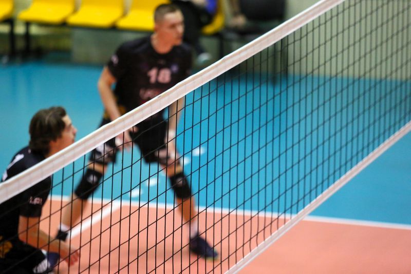 a volleyball net with two volleyball players in the backround