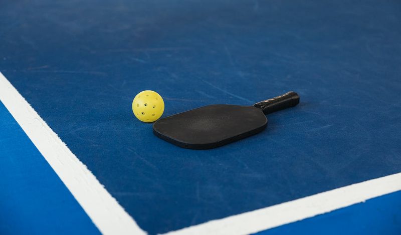 a black pickleball paddle on a court