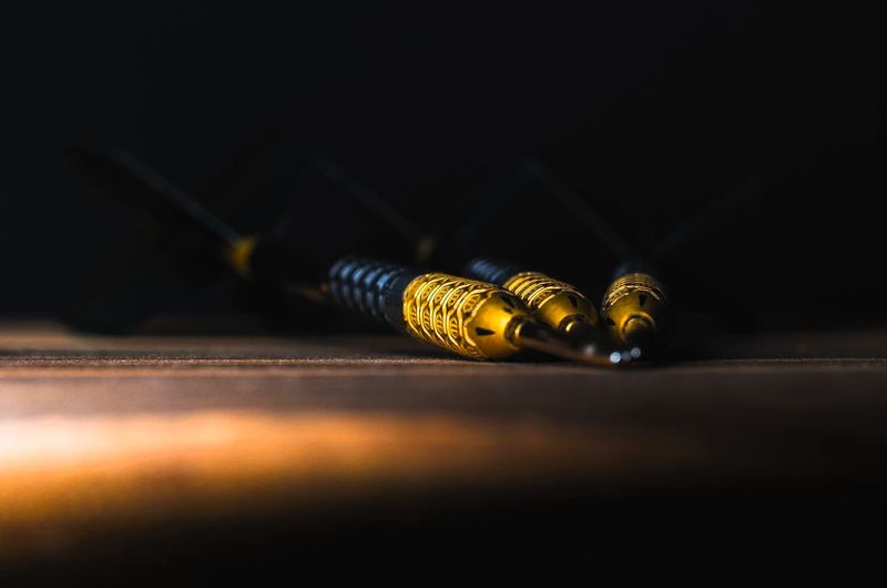 three dart tips in front a dark background