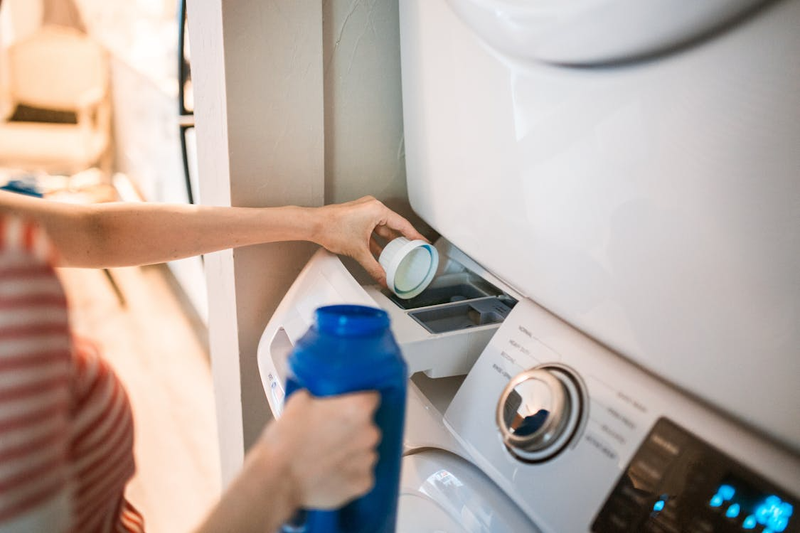 a person placing fabric softener into a washing machine