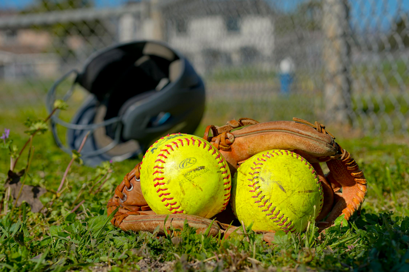 two yellow softballs inside a softball glove