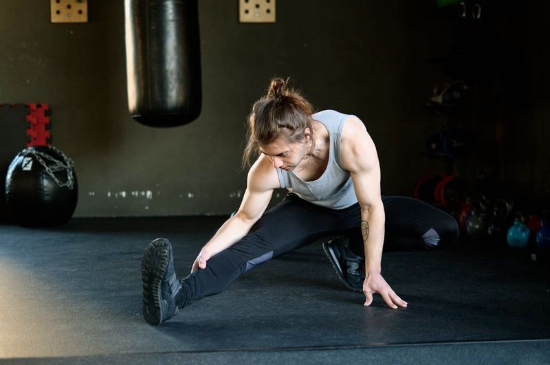 An athletic male stretching in a gym