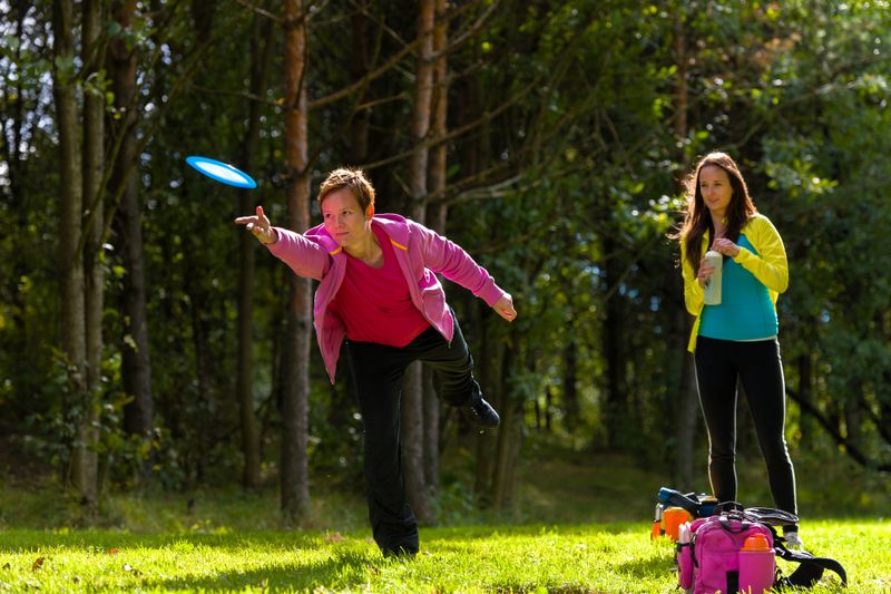two adult females practicing disc golf throws
