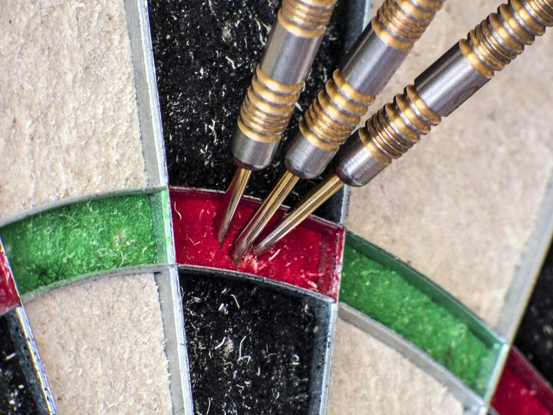 a grouping of three darts in the triple 20 spot on a dart board