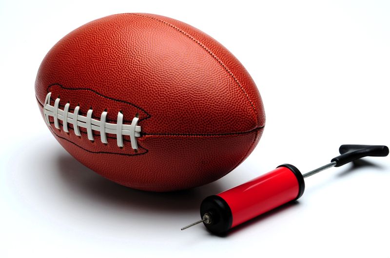 an American football next to a ball pump