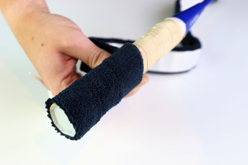 a hand taping the butt end of a hockey stick with hockey tape