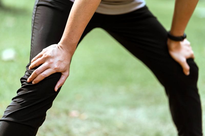 a female with her hands on her knees wearing nylon track pants
