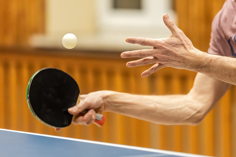 an adult male ping pong player about to hit a ping pong with a paddle