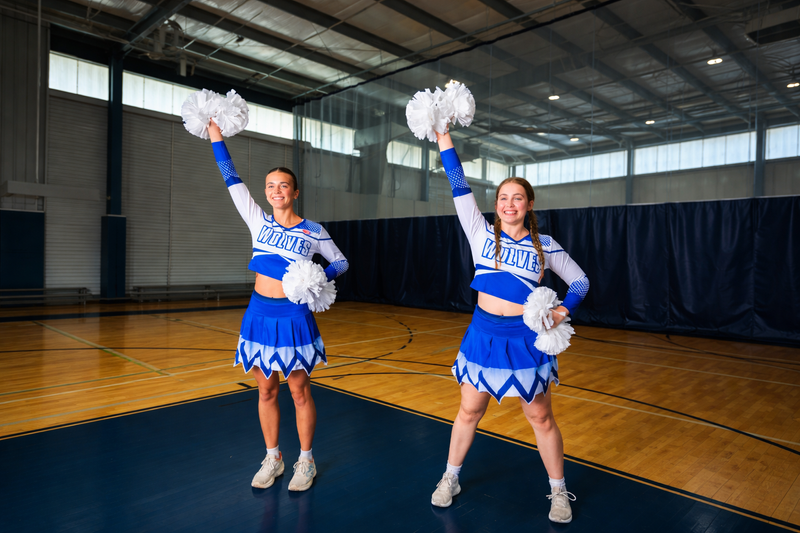 two cheerleaders wearing blue and white cheer uniforms