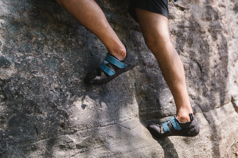 a close up of a man rock climbing wearing rock climbing shoes