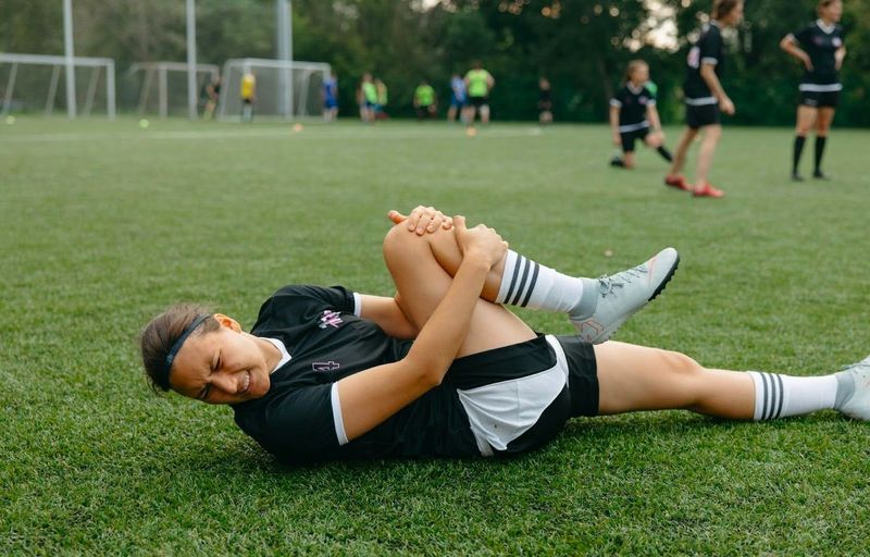 a female soccer player stretching on a soccer field