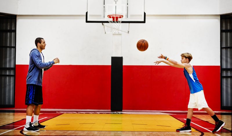 a basketball coach running passing drills with a youth basketball player