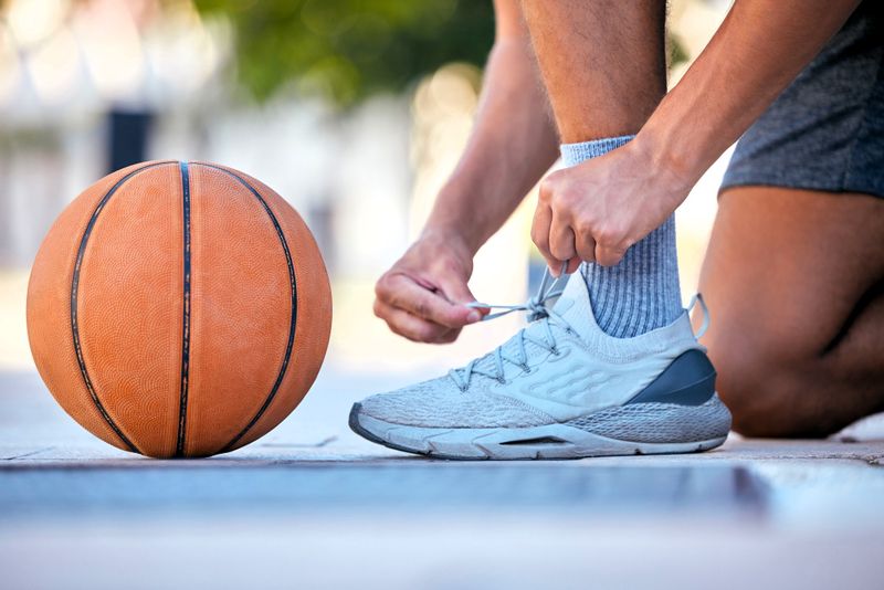 a basketball player tying laces on their basketball shoes next to a basketball