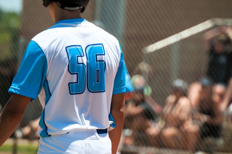 the back of an adult male wearing a blue and white baseball jersey