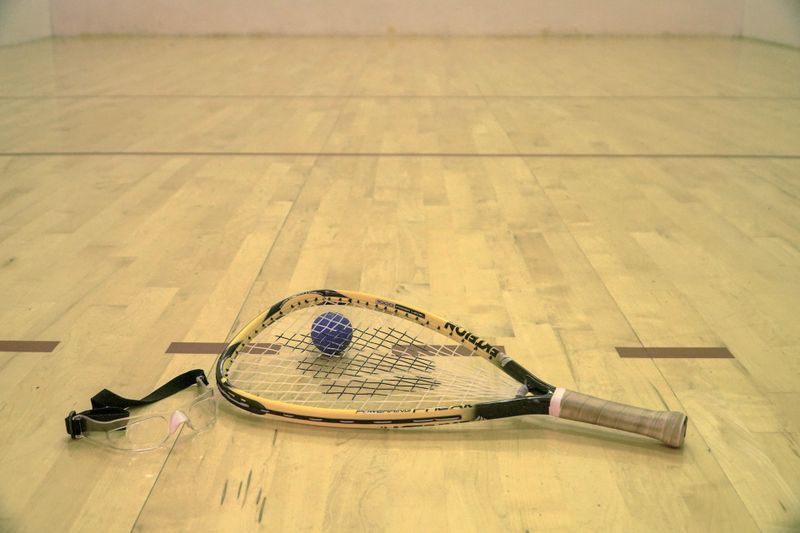 a racquetball racquet lying on top of a racquetball next to goggles