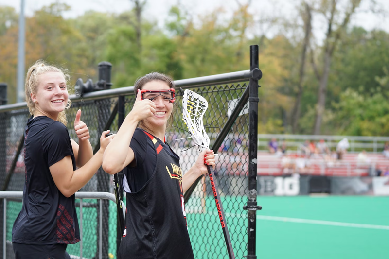 two female lacrosse players giving a thumbs up