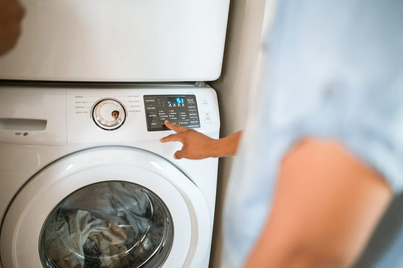 a person setting washing machine settings